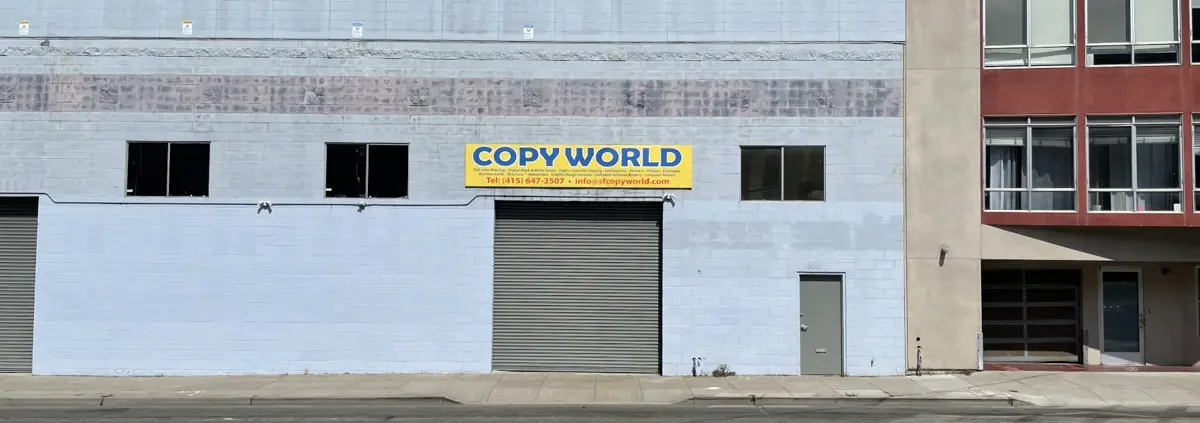 A photo of a gray building with a yellow sign that says Copyworld