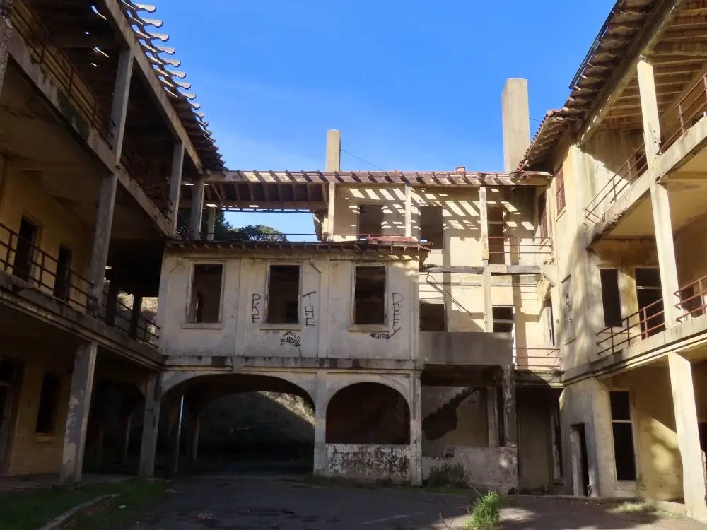 A view up from inside a decaying courtyard. The sky is intensly blue.