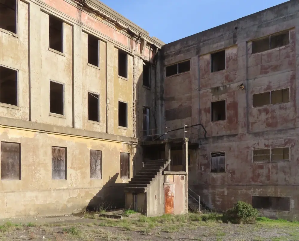 The inside corner of an abandoned building with stairs that don't connect to anything