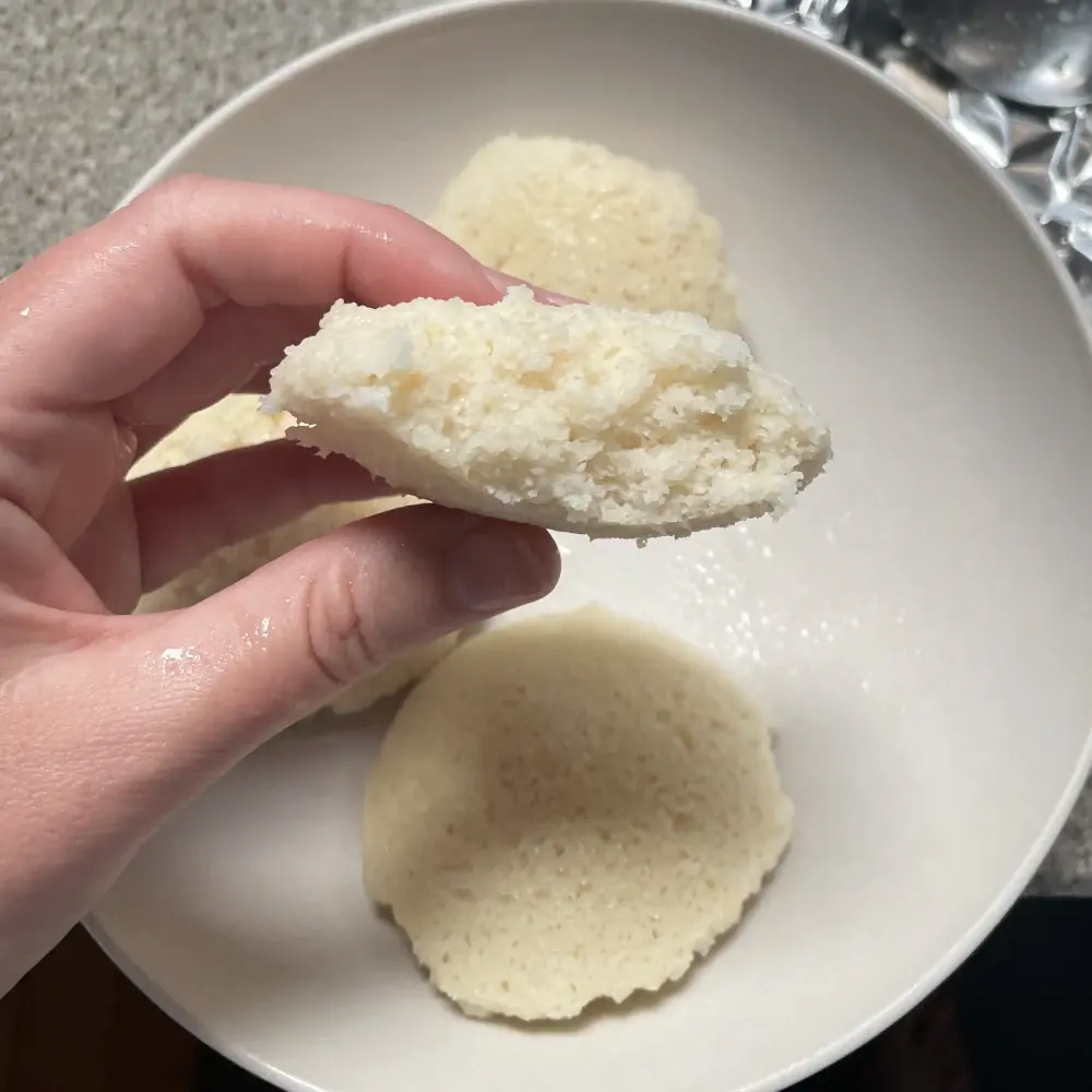 An idli broken in half, showing the crumb inside