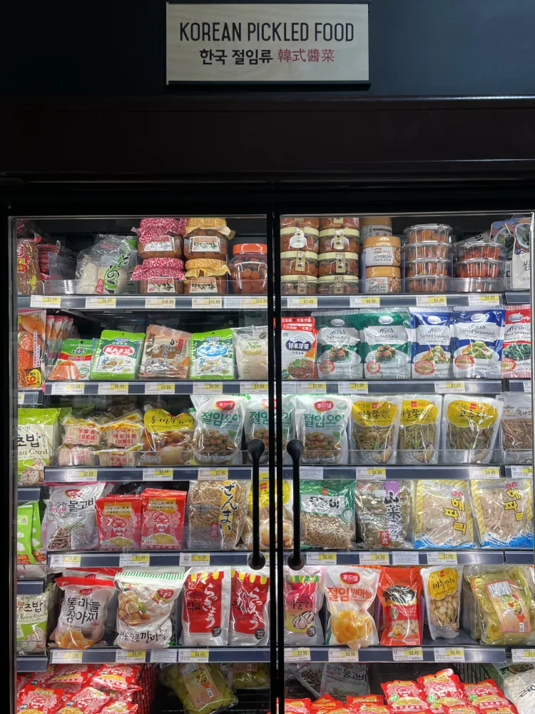 A glass-fronted fridge cabinet displaying a variety of packaged pickled vegetables