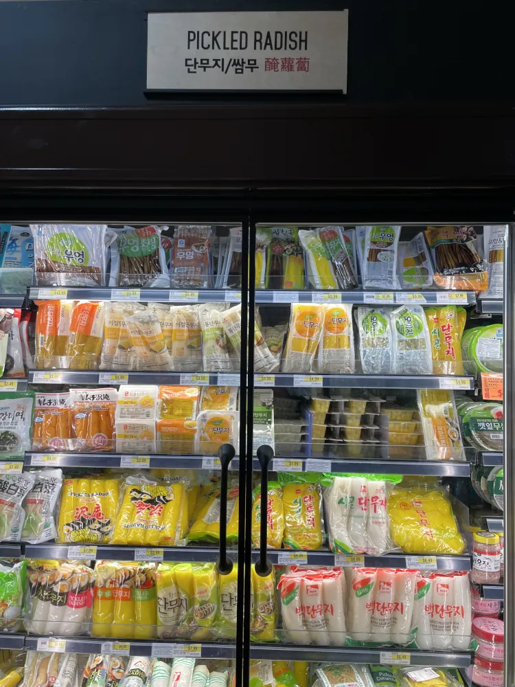A glass-fronted fridge cabinet displaying a variety of packaged pickled radish