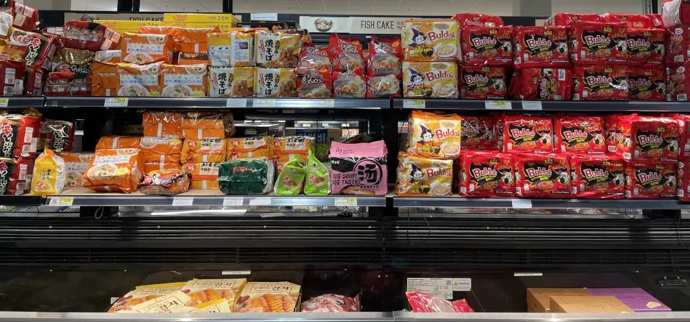 Variety of colorful packaged ramen on top of a cold display cabinet