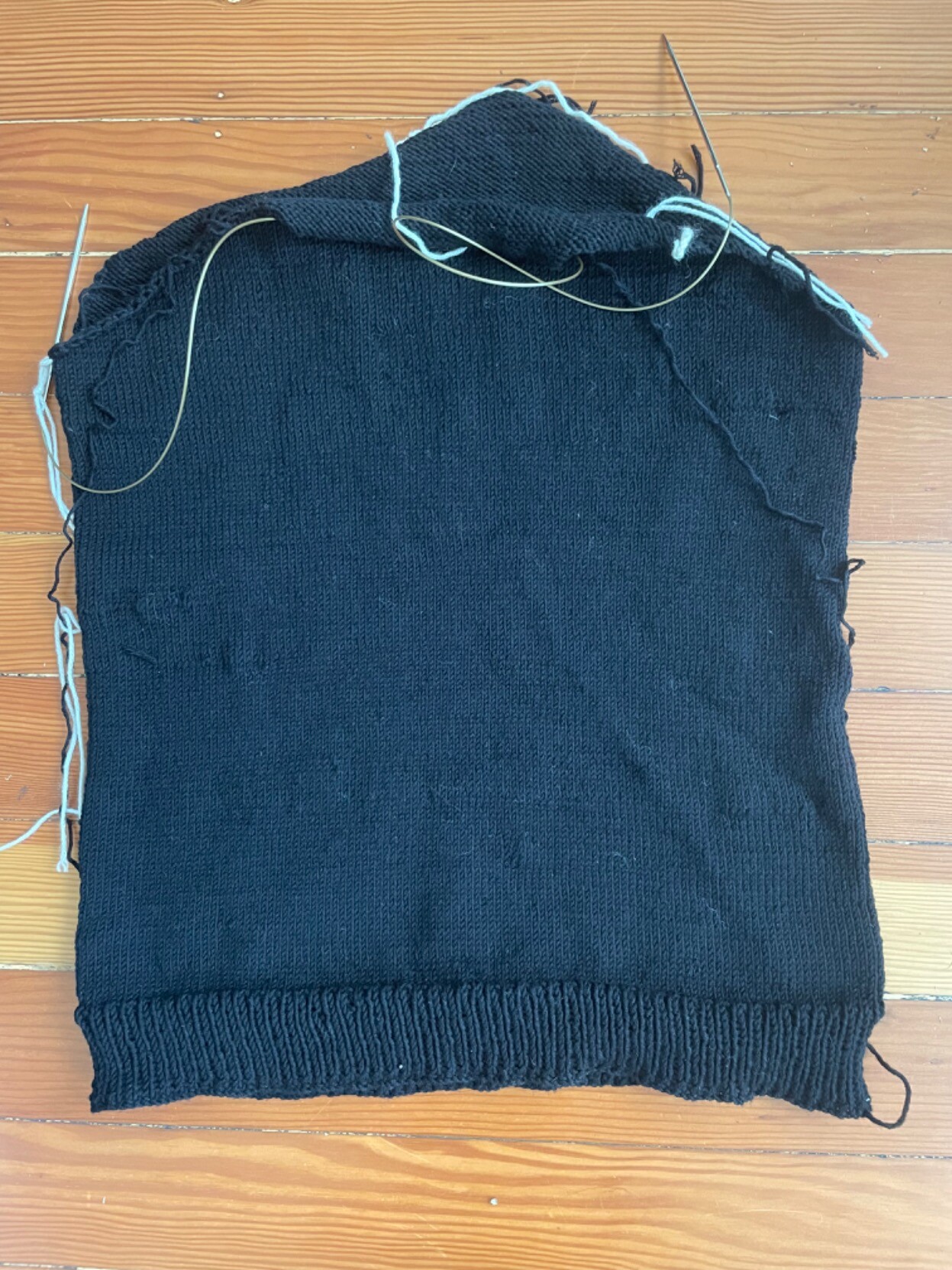 The body of a black sweater, still on the needles. The collar and sleeves aren’t done yet.