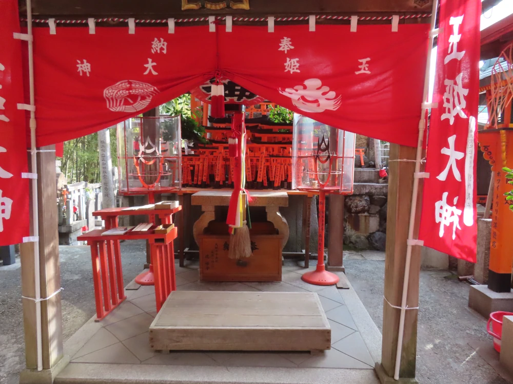 An altar with red hangings, red decorations, and tons of little red torii stacked on it