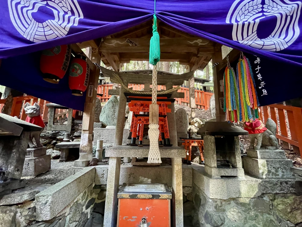 A shinto altar with a purple entrance way and thousands of folded paper cranes hung to the side like garlands.