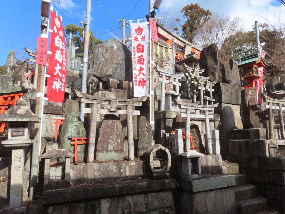 A group of stone shrines, mostly little stone torii but some red ones as well