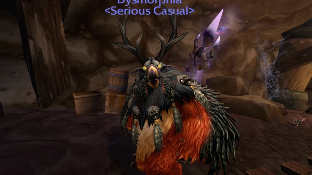 A red, humanoid owlbeast with glowing yellow eyes and deer antlers growing from its head looks at the camera. Screenshot from World of Warcraft.