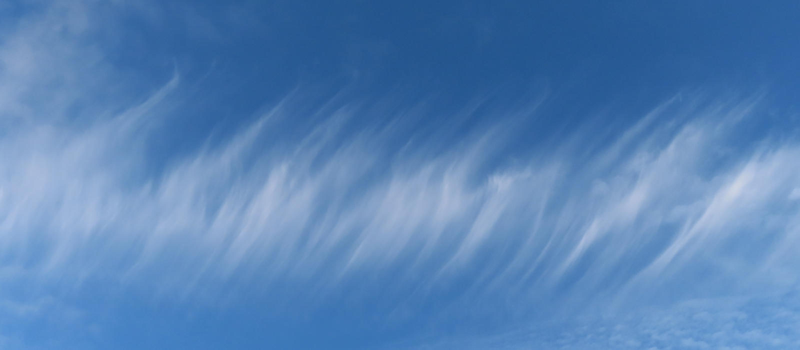 A photograph of a blue sky with thin cirrus clouds that look like a series of slashes. Own work 2023.