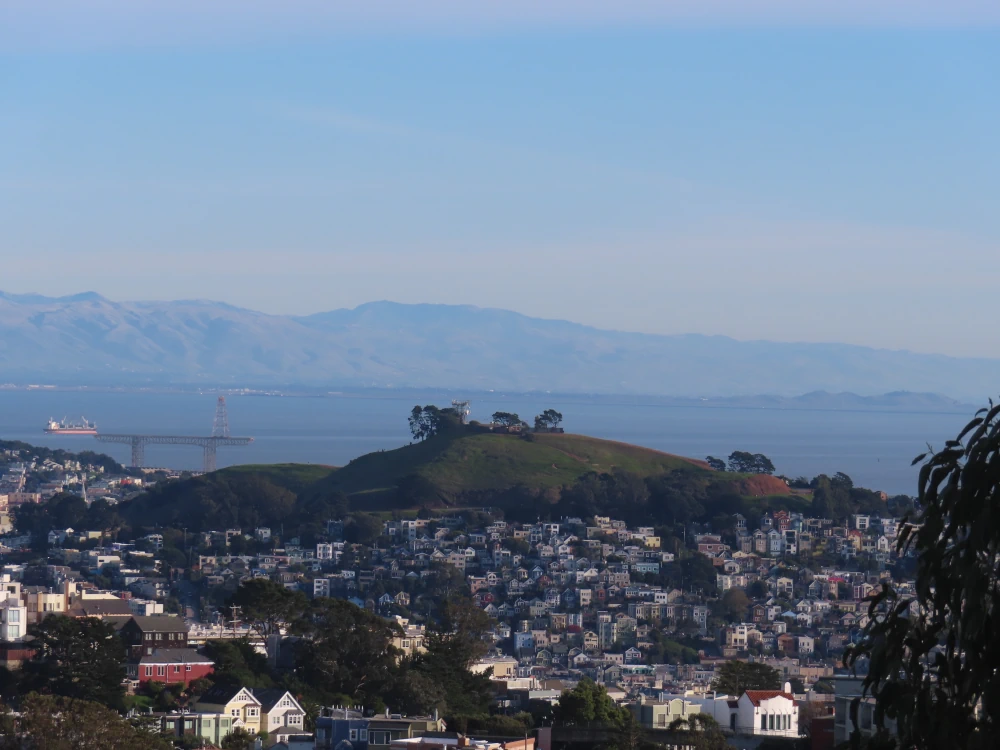 View of a green hill rising out of a hillside encrusted with little houses