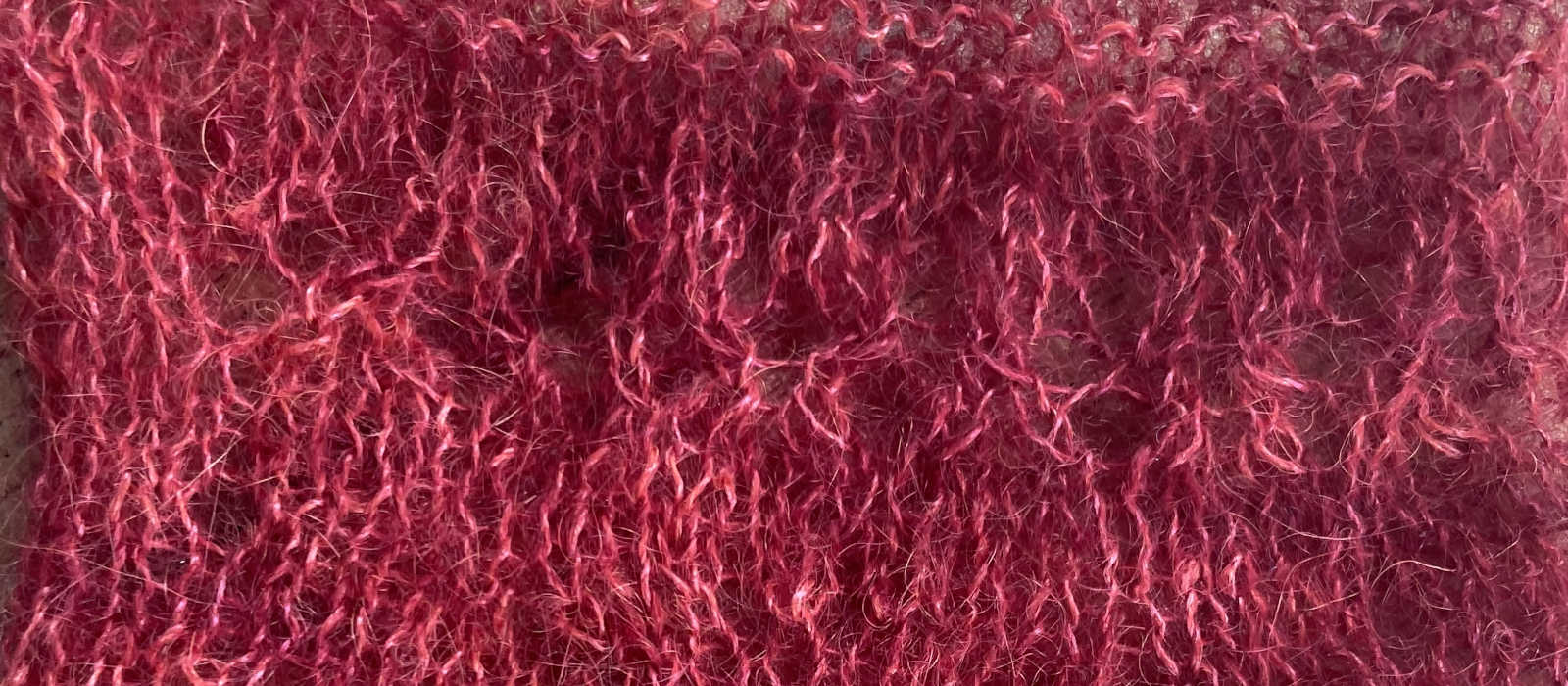 Close-up photo of a yarn swatch made of a fuzzy red yarn.
