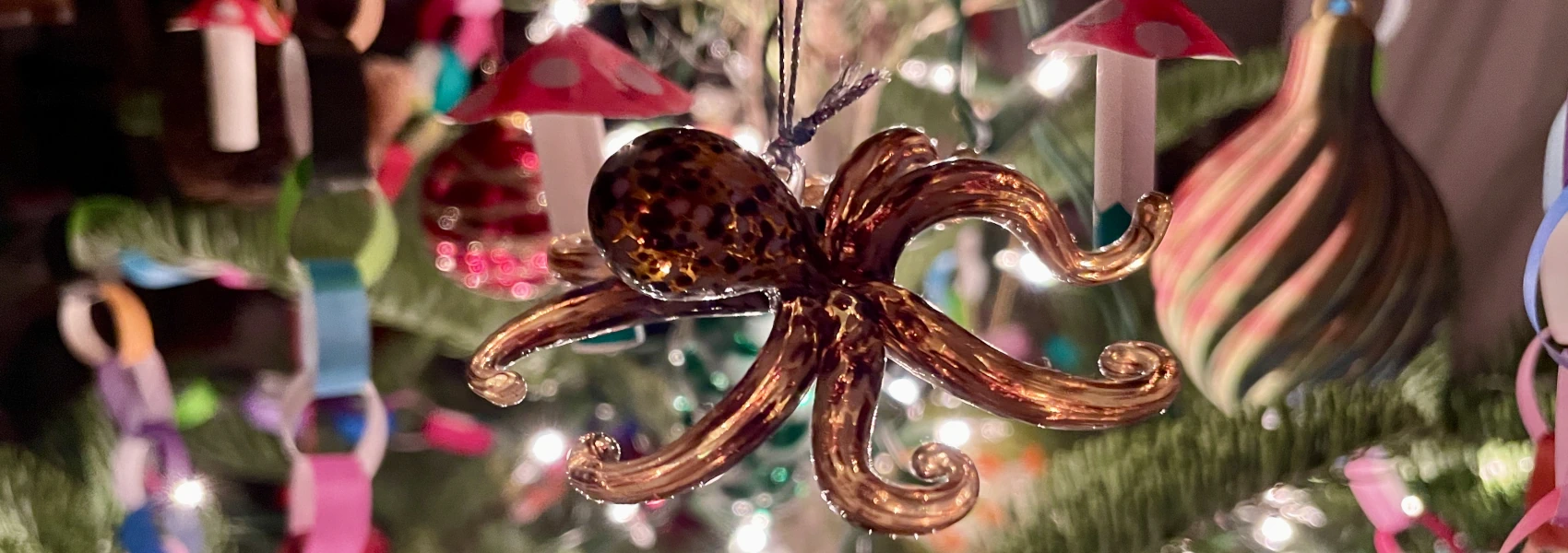 Closeup photo of a glass octopus ornament hanging on a Christmas tree