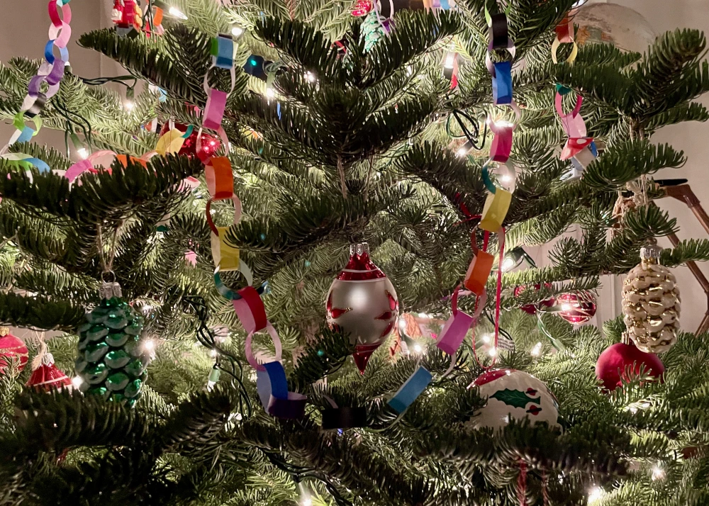 Paper chains frame several different glass pinecone baubles on a Christmas tree